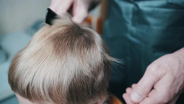 Closeup of a Barber Combing the Hair of an Unrecognizable Boy