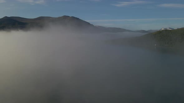 Drone flying through cloud and fog surrounded by mountains and forests