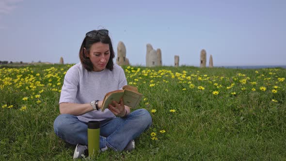 A Girl Reads a Book Sitting on the Green Grass