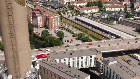 Industrial chimney and street traffic of Swedish town, aerial drone view