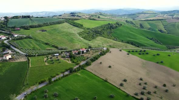 Aerial shot of a hilly landscape with land fields and estates