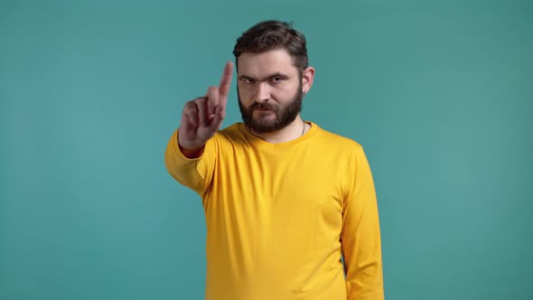 Portrait of Serious Man in Yellow Showing Rejecting Gesture By Stop Finger Sign