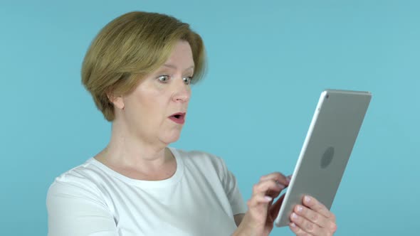 Old Woman in Shock While Using Tablet Isolated on Blue Background