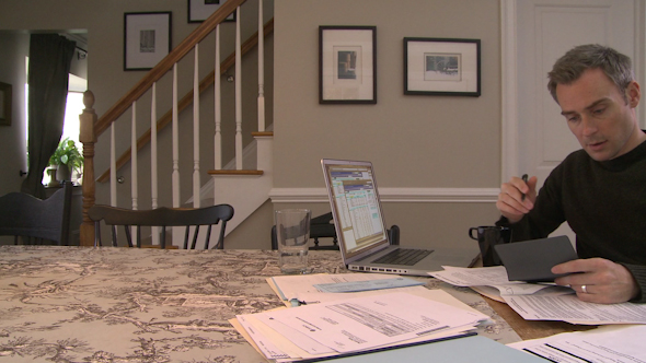 A Man Going Over His Bills On His Dining Room Table (2 Of 3)