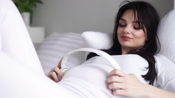 Pregnant Woman Listening Pregnancy Music With Headphone On Belly