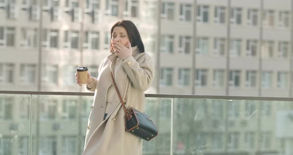 Portrait of Tired Caucasian Brunette Woman Yawning and Drinking Coffee