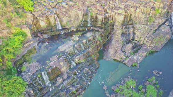 Drone Shows Blue Pond with Waterfall Cascade Among Rocks