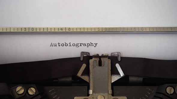Typing word Autobiography on retro typewriter. Close up.
