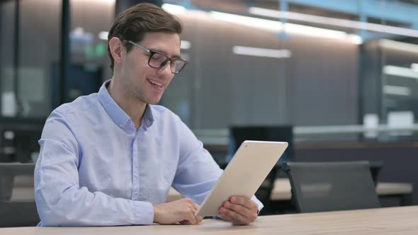 Young Man Making Video Call on Tablet at Work