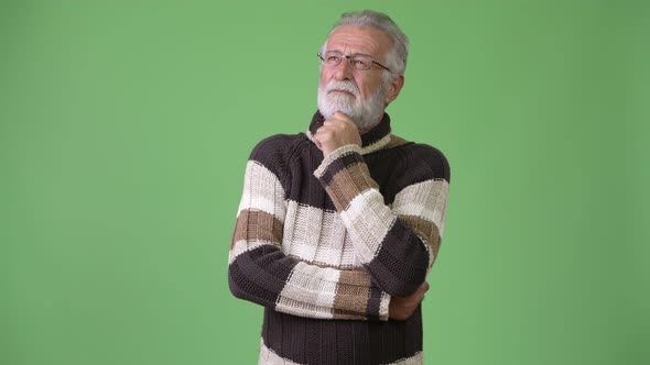 Handsome Senior Bearded Man Wearing Warm Clothing Against Green Background