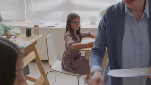 Teacher Giving Test Sheets to Children in Class