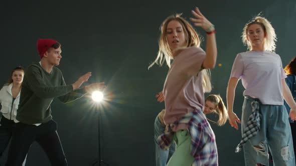 Portrait of Young Actors Dancing on Dark Stage with Lights Looking at Camera