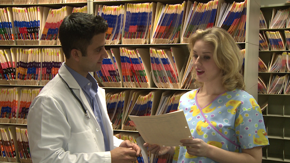Doctor And Nurse Discuss Patient's Chart (2 Of 3)