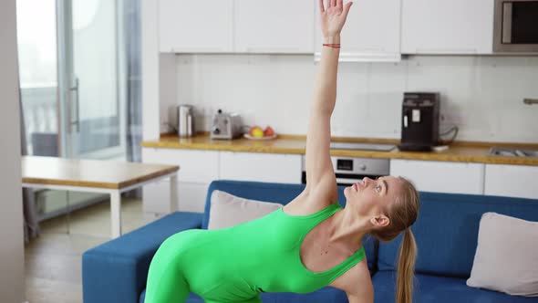 Slender Lady in Green Tracksuit Performs Standing Asanas Trikonasana The Triangle Pose Using Yoga