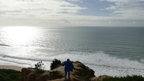 Man Climb on a Cliff Above the Ocean
