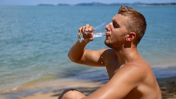 Man Drinking Water on the Beach in Slow Motion