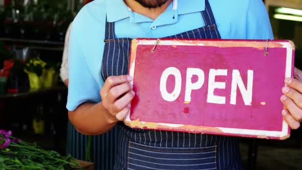 Male florist holding open signboard