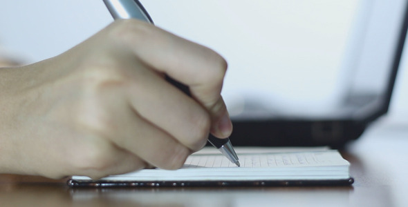 Woman Typing on Laptop and Making Notes alt