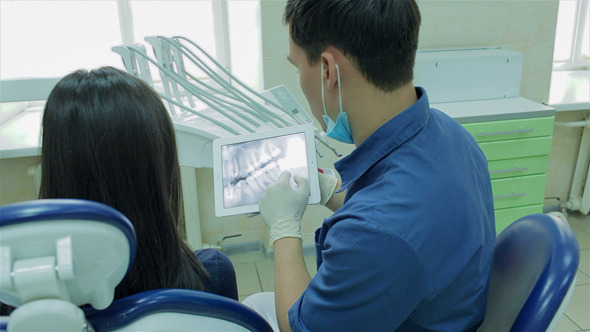  Dentist Shows A Patient X-ray On The Tablet