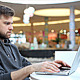 Man Working at a Laptop in a Shopping Center - VideoHive Item for Sale