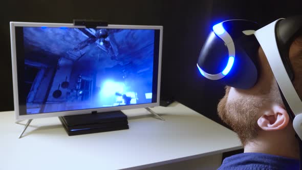 Person Sits in Virtual Reality Helmet Look Closeup Front of Monitor with Game