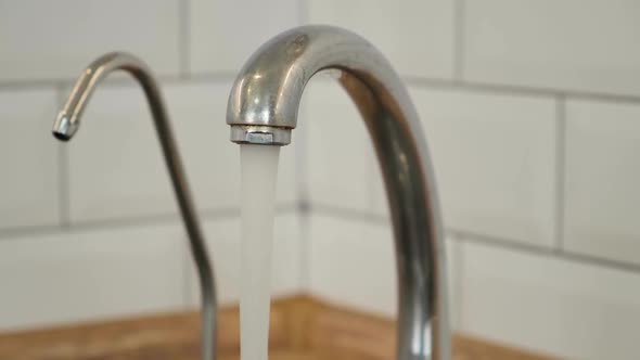 Close Up Tap Water Flowing From Kitchen Faucet. Water Consumption, Hygiene and Faucet Manufacturing.