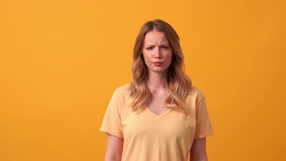 Displeased blonde woman wearing yellow t-shirt looking at the camera