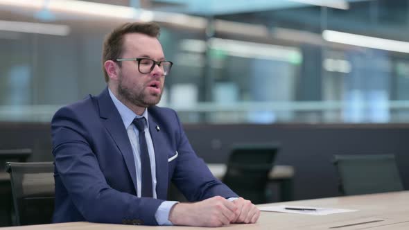 Middle Aged Businessman Feeling Worried While Sitting in Office