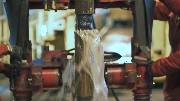 Connecting of Drill Pipes on the Drilling Platform. Water Flows Up From the Well. In the Background