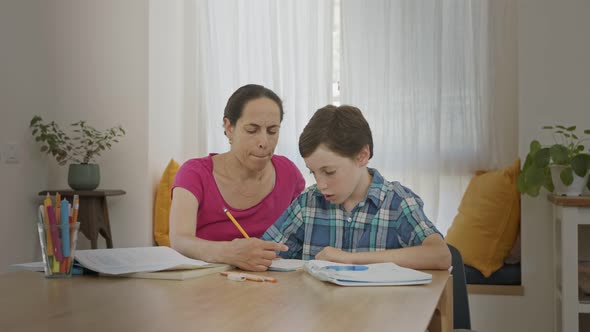 Mother helping her young son prepare homework during homeschooling