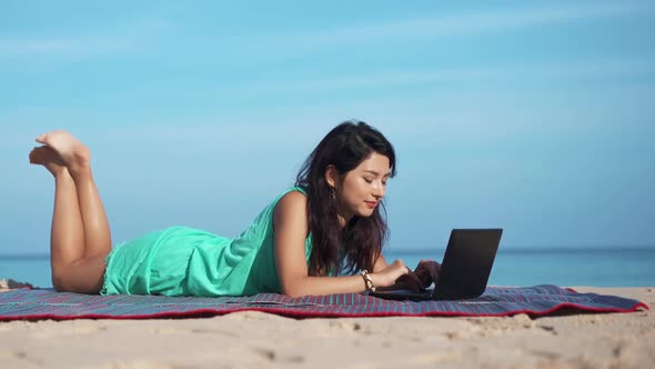 Portrait of Pretty Woman on Beach in Front of Laptop