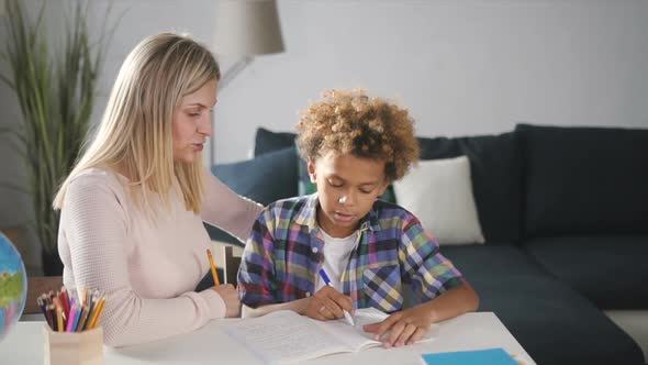 Laughing Mother Is Showing To Son Right Decision and Answer on Question in School Homework.