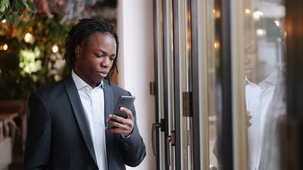 Serious Smartly Dressed Man Talking By Phone and Working at Cafe