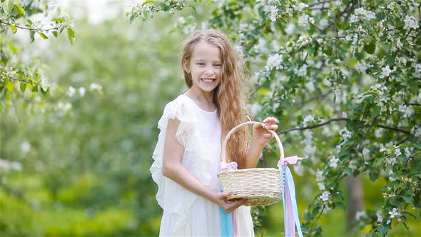 Adorable Little Girl in Blooming Apple Garden on Beautiful Spring Day