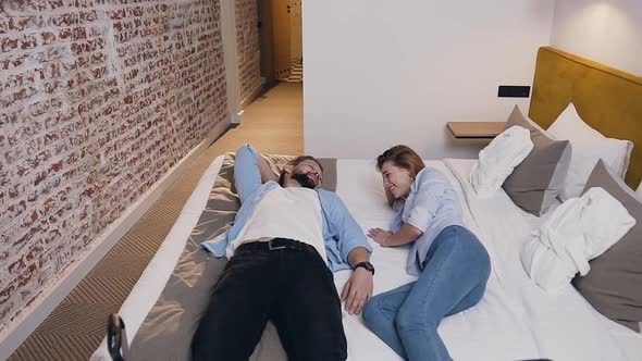 Young Amorous People Resting on their Hotel Bed and Talking with Each Other