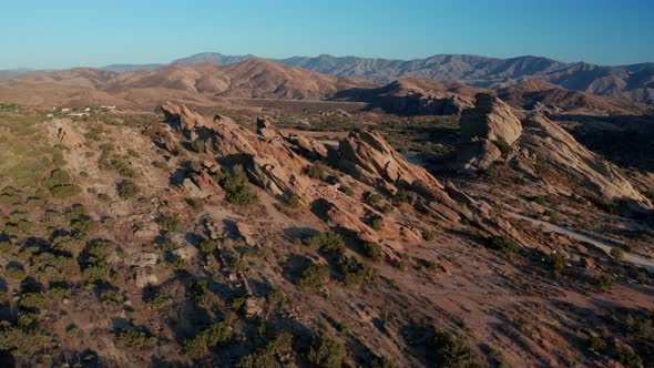 Aerial footage of mountains and dry land with blue cloudy sky in the background. 