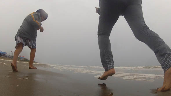 Mother And Son Running On A Rainy Beach