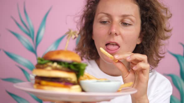 Young Caucasian Enjoys Her Lunch of Doubledecker Vegan Burger and French Fries