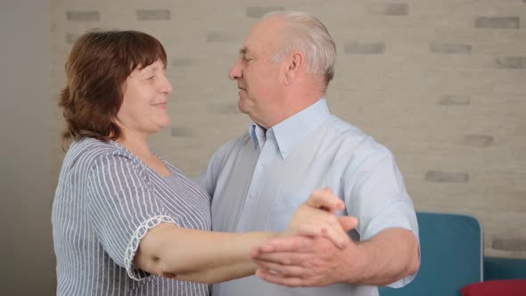 Senior Couple Dance in the Living Room and Talk About Their Happy Days Together.