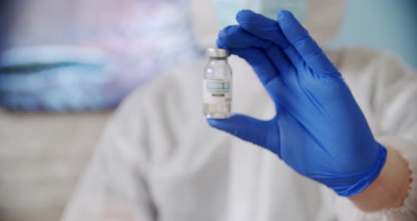 Blured Doctor's Hand Holds Ampoule Vaccine Bottle at the Hospital