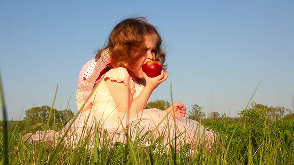 Little Girl Eating Apple On Meadow alt