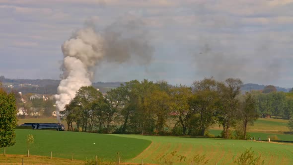 View of An Antique Steam Passenger Train Traveling Thru Trees and Farmlands