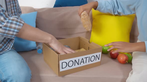 Close Up of Young Volunteers Doing Community Service Packing Donation Box with Food