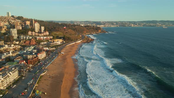 Aerial view flying across Reñaca golden sand waterfront with sunny scenic tourism retreat beach ocea