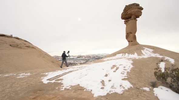 Man walking in the Utah desert holding camera on gimbal