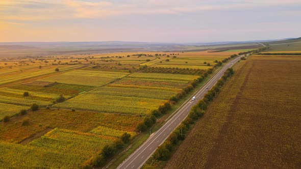 Aerial drone view of nature in Moldova at sunset. Wide fields, road with moving cars, trees