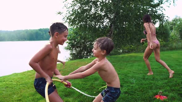 Mother with Father and Two Children Playing on the Lawn Pouring Water Laughing and Having Fun