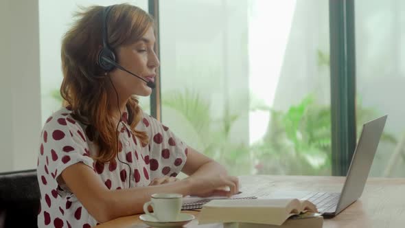 Side View of Young Business Woman Wearing Headset Communicating By Video Call
