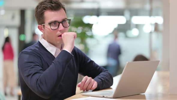 Sick Young Businessman with Laptop Coughing 