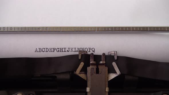 Typing alphabet letters A B C D E F G H I J K L M N O P Q on retro typewriter. Close up.